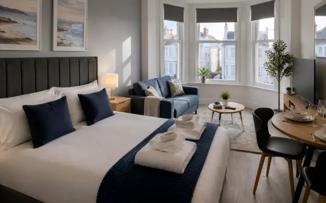 Freshly made bed and reset living space in a guest-ready serviced apartment